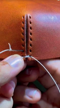 someone is stitching together the leather on their handmade case with scissors and thread