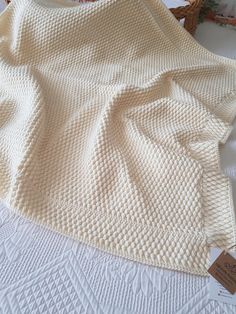 a white knitted blanket sitting on top of a bed