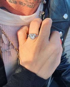 a man wearing a diamond ring on his left hand and holding a chain around his neck