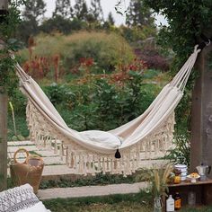 a white hammock hanging in the middle of a garden