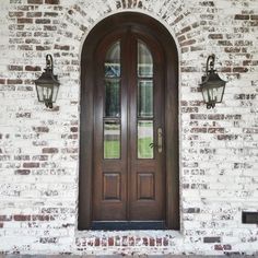 two lights are on the side of a brick building and there is a double door