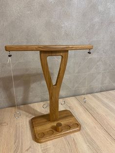 a wooden stand with two pegs attached to it on top of a wood floor