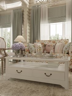 a living room filled with furniture and a chandelier hanging from the ceiling over a coffee table