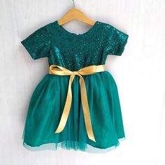 Emerald green sequin flower girl dress with matching dark green tulle skirt. The back is closing with invisible zipper and gold satin ribbon with tie at the backHave a hunter green, emerald green or forest green wedding theme? Then this is a perfect dress for your cute little flower girl. The tutu dress can also be a Birthday Dress, Christmas dress or to attend semi formal to formal occasionIff you want to have a different color for the tutu skirt or ribbon just leave me a note at the 'message t Emerald Green Flower Girl Dress, Emerald Green Flower Girl, Green Flower Girl Dress, Green Tulle Skirt, Green Flower Girl Dresses, Forest Green Wedding, Black Flower Girl Dress, Sequin Flower Girl Dress, Girls Navy Dress