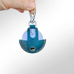 a hand holding a blue and white keychain with a hole in the middle