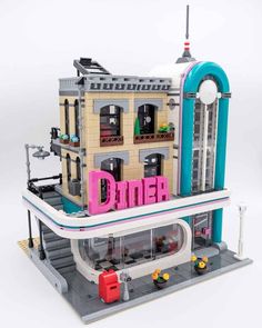 a lego model of a diner with neon pink letters on the front and blue roof