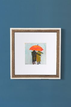 two people holding an orange umbrella in front of a painting on the wall with blue walls