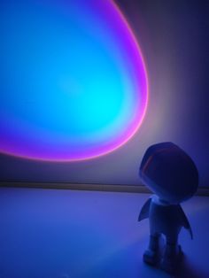 a small toy is standing in front of a blue and purple light that appears to be an object