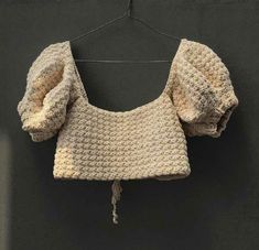 a crocheted top hanging on a clothes line