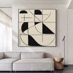 a living room with a white couch and black and white painting on the wall