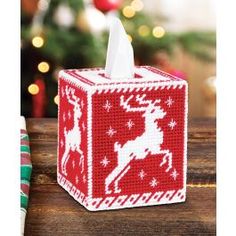 a tissue dispenser on a wooden table with christmas decorations in the background