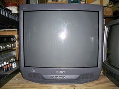 an old sony television sitting on top of a wooden table next to other electronic devices