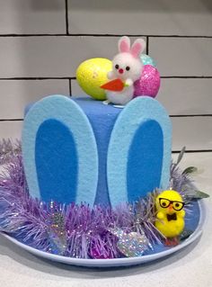 there is a blue cake with purple frosting and decorations on the top, along with an easter bunny figurine