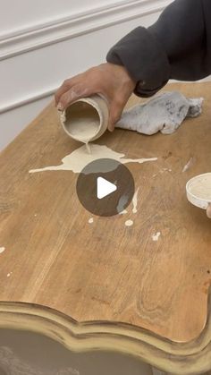 a person is painting a wooden table with white paint