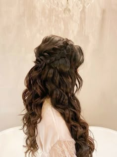 the back of a woman's head sitting in a bathtub with long curly hair