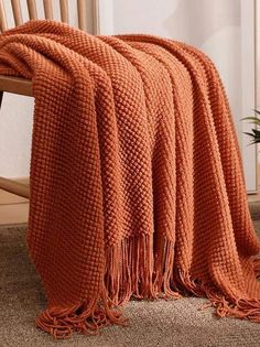 an orange blanket sitting on top of a wooden chair