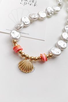 🐚 our 𝓝𝓪𝓾𝓽𝓲𝓬𝓪𝓵 𝓒𝓸𝓵𝓵𝓮𝓬𝓽𝓲𝓸𝓷 is here! 🐚🤍✨🥥 This beautiful golden clam choker will add a touch of elegance to your summer outfit! 😎

MATERIALS
⭐ faux pearl beads
⭐ gold plated beads
⭐ glitter polymer clay beads
⭐ 18k gold plated clam pendant

DETAILS
Closure: Lobster clasp
Size: 17.5 Inches

CARING TIPS
🤍 Keep your jewelry dry and away from perfumes or any harsh chemicals
🤍 Store your jewelry separately, and avoid wearing it if you are going to work out.

If you have any questions, please feel free to message me.
Thank you so much for visiting my shop!
Have fun creating your favorite combinations and enjoy your new jewelry! ♥♥♥ Pearl Necklaces With Spacer Beads For Beach, Adjustable Gold Beaded Shell Necklace, Gold Choker With Round Beads For The Beach, Elegant Gold Shell Necklace With Round Beads, Beach Pearl Jewelry With Gold Beads, Gold Choker With Colorful Beads For Beach, Gold Pearl Beaded Necklaces With Colorful Beads, Pearl Jewelry With Gold Beads For Beach, Gold Choker With Colorful Round Beads