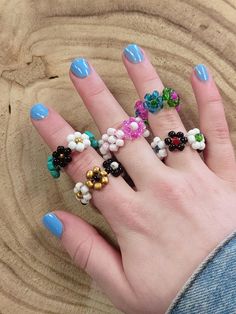 a woman's hand with five different rings on it, and one has blue fingernails