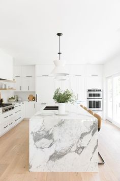 a kitchen with marble counter tops and white cabinets, along with an island in the middle