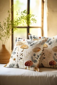 two pillows sitting on top of a bed next to a vase with plants in it