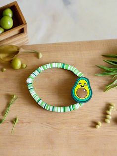 a close up of a bracelet on a table with olives and an object in the background