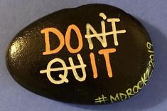 a black rock with the words do it out painted on it in orange and white