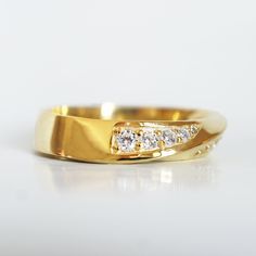 a yellow gold ring with three diamonds on the side, set against a white background