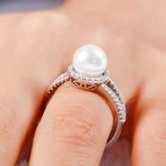 Pearl-the queen of gems and the gem of queens. Treat yourself with this elegant ring. Crafted in sterling silver, the ring features a 8mm faux pearl set in a glistening halo of round stones and its classic split shank. The elegant and timeless look won't be out of date in along time. This ring will be a nice holiday gift for Mom, sister,friend or yourself! Treat yourself or surprised her with this dainty piece. It won't disappoint you!Carat Weight: 4.2 ctStone Size: 8 mmStone Type: Jeulia® StoneNumber of Stones: 1 Stone Color: Diamond WhiteStone Shape: RoundCarat Weight: 0.58 ctStone Size: 1.1 mmStone Type: Jeulia® StoneNumber of Stones: 58 Stone Color: Diamond WhiteStone Shape: RoundWeight: 4.3 gWidth: 2.42 mmHeight: 8 mmThickness: 1.27 mmMaterial: 925 SilverPlating Color: Silver Elegant Pearl Drop Ring For Anniversary, Formal Pearl White Open Pearl Ring, Formal Pearl White Open Ring, Fine Jewelry Diamond White Pearl Rings, Fine Jewelry Pearl Ring In Diamond White, Elegant Open Pearl Ring, Elegant Diamond Pearl Ring For Promise, Elegant Diamond Pearl Promise Ring, Elegant White Gold Pearl Promise Ring