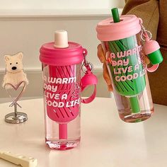 two water bottles and a toothbrush sitting on a table next to each other, one with a plastic cup in the shape of a flaming