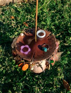 an upside down tree stump with decorations on it in the grass, and a stick sticking out of its hole