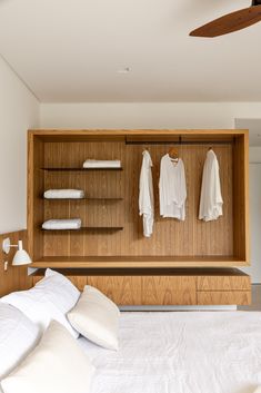 a bed sitting under a wooden shelf next to a ceiling fan