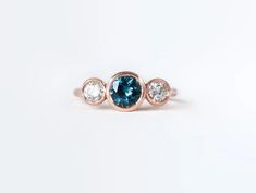 three stone ring in rose gold with blue and white diamonds