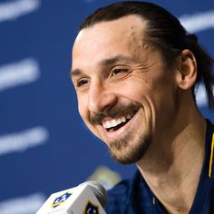 a man with a goatee smiles as he holds a microphone in front of him