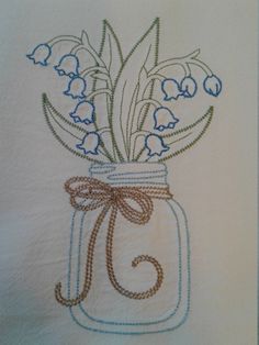 a jar filled with blue flowers on top of a white table cloth covered in thread