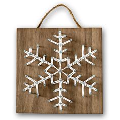 a snowflake is hanging on a wooden plaque