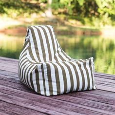 a green and white striped bean bag sitting on top of a wooden deck next to water