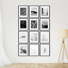 a white wall with black and white pictures on it in front of a floor lamp