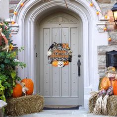 a front door decorated for halloween with hay bales and pumpkins