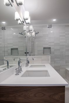 a bathroom with two sinks, mirrors and lights on the wall above them is shown