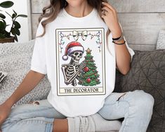 December 7th is the last day to order for guaranteed shipping by Christmas! Please make sure your address on file is correct when ordering. Some elements in graphic created with the assistance of AI Skeleton Christmas Tarot Card Shirt - Festive Holiday Apparel This Skeleton Christmas Tarot Card Shirt is the perfect blend of holiday spirit and mystic vibes! Featuring a unique tarot card design with festive skeleton elements, this shirt is sure to make a statement during the holiday season. Made f Christmas Tarot Cards, Christmas Tarot, Witchy Christmas, Ugly Christmas Tree, Unique Tarot Cards, Tarot Card Shirt, Tarot Card Design, Skeleton Christmas, Christmas Tree Decorating