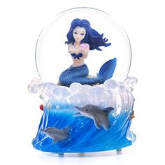 a little mermaid sitting on top of a dolphin in a snow globe with two dolphins