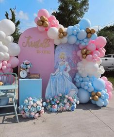 there is a balloon arch that has princess balloons on it and flowers in the foreground