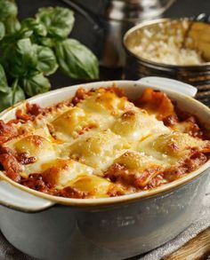 a casserole dish with meat and cheese in it on a table next to other dishes