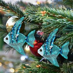 two blue fish ornaments hanging from a christmas tree