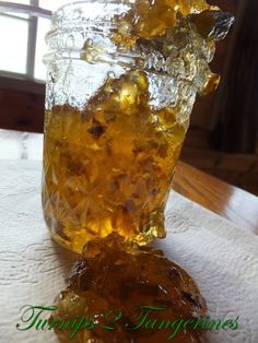 a glass jar filled with liquid sitting on top of a white table cloth next to a window