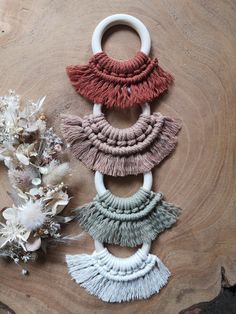 three tasseled pieces of fabric sitting on top of a wooden table next to flowers