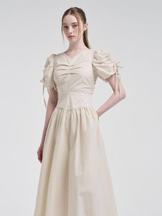 This product presents a meticulously crafted Front Tuck Shirring Dress that exudes a blend of sophistication and delicate charm. The design highlights a structured bodice with artistic tuck details, offering a touch of classic couture. Emphasizing a feminine aesthetic, the dress features enchanting sleeve details and a fluidly draped skirt that together create an air of understated elegance. - This dress showcases a beautifully fitted bodice with tuck details that enhance the garment's structure and form.- It is accentuated with puff sleeves that boast shirring and tie details, adding a romantic flourish to the piece.- The skirt part of the dress flows gracefully, thanks to its gathered waist that lends volume and movement.- It also includes a unique adornment, with a handmade Cali me Feminine Puff Sleeve Dress With Ruched Bodice, Elegant Formal A-line Puff Sleeve Dress, Formal Midi Dress With Gathered Neckline And Fitted Bodice, Elegant Dress With Fitted Waist And Square Neck, Chic Midi Dress With Gathered Sleeves And Sweetheart Neckline, Chic Midi Dress With Sweetheart Neckline And Gathered Sleeves, Elegant Square Neck Dress With Fitted Waist, Puff Sleeve Dress With Pleated Bodice And Square Neck, Fitted Midi Dress With Ruched Bodice And Puff Sleeves