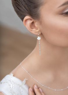 a woman in a white dress wearing a necklace and earrings