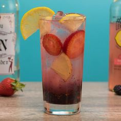 a glass filled with ice and strawberries next to two bottles