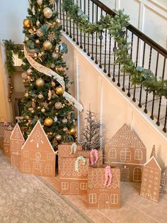 gingerbread houses are on the floor next to a christmas tree and stair railings